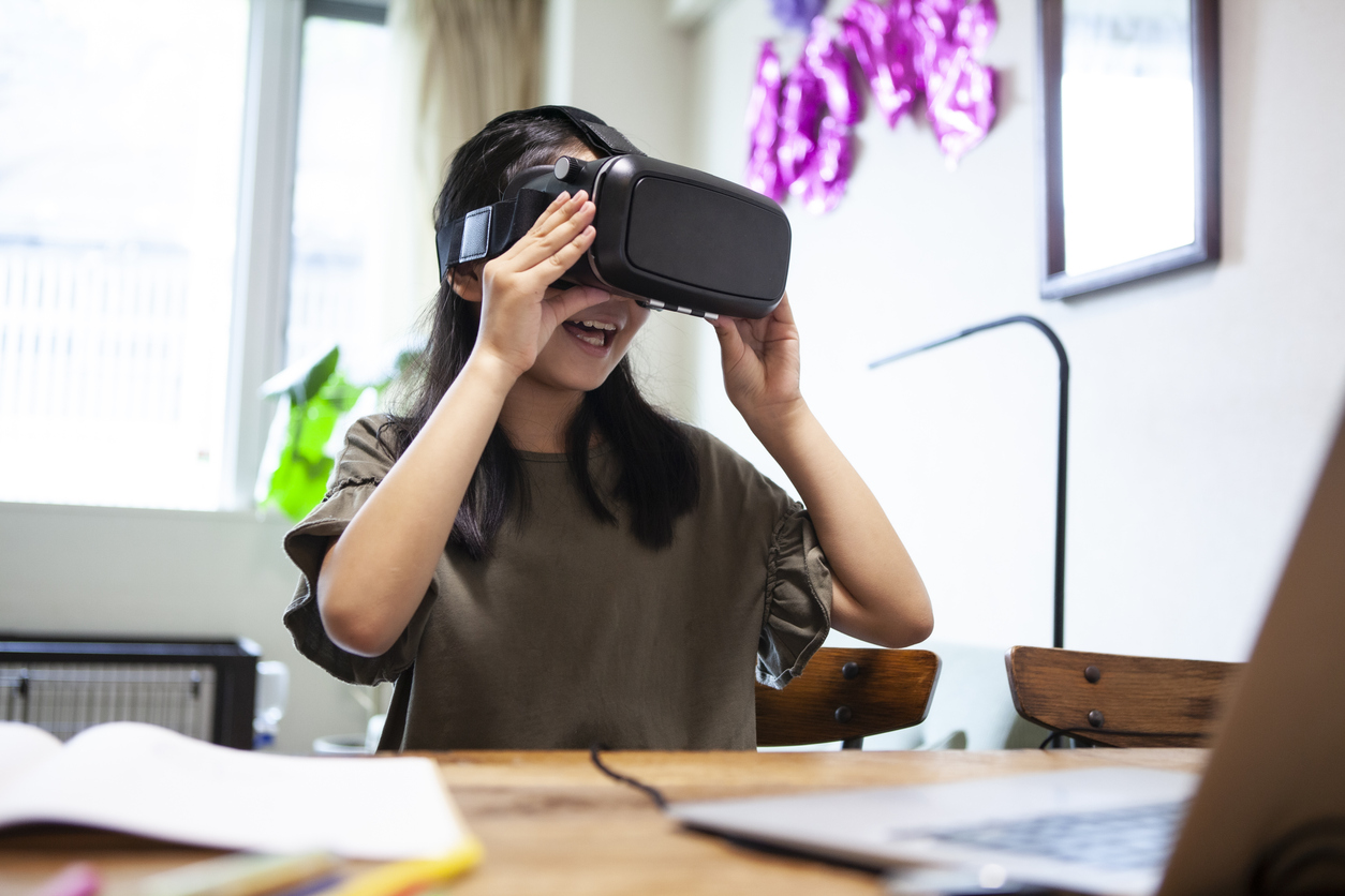 A girl wearing VR goggles and playing on the table