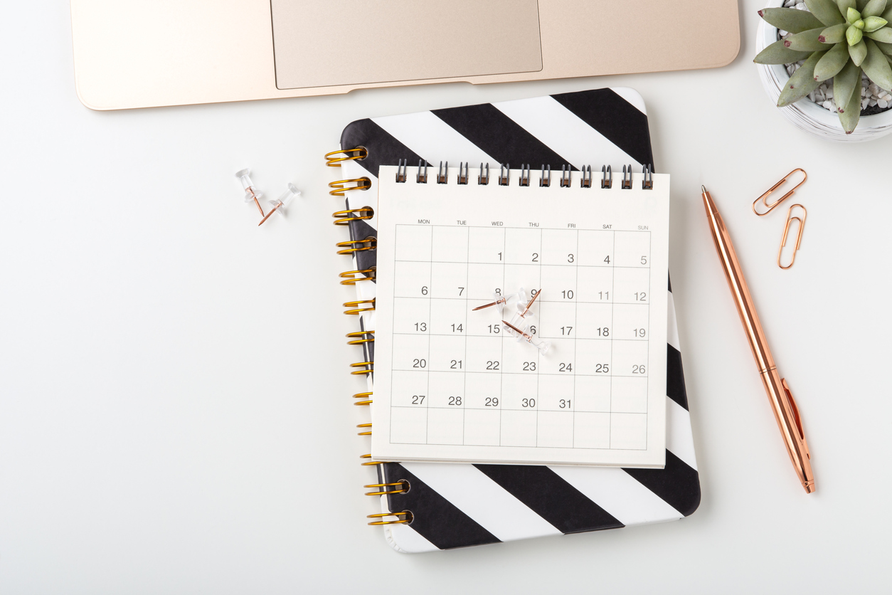 Calendar on notebook, business meeting schedule concept Calendar on notebook with pen and laptop on white desk, flat lay, business meeting, event planning concept
